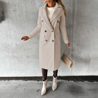 Cappotto beige elegante donna, doppio petto, abbinato a stivali chiari e borsa a mano, su sfondo grigio. Moda autunnale chic.