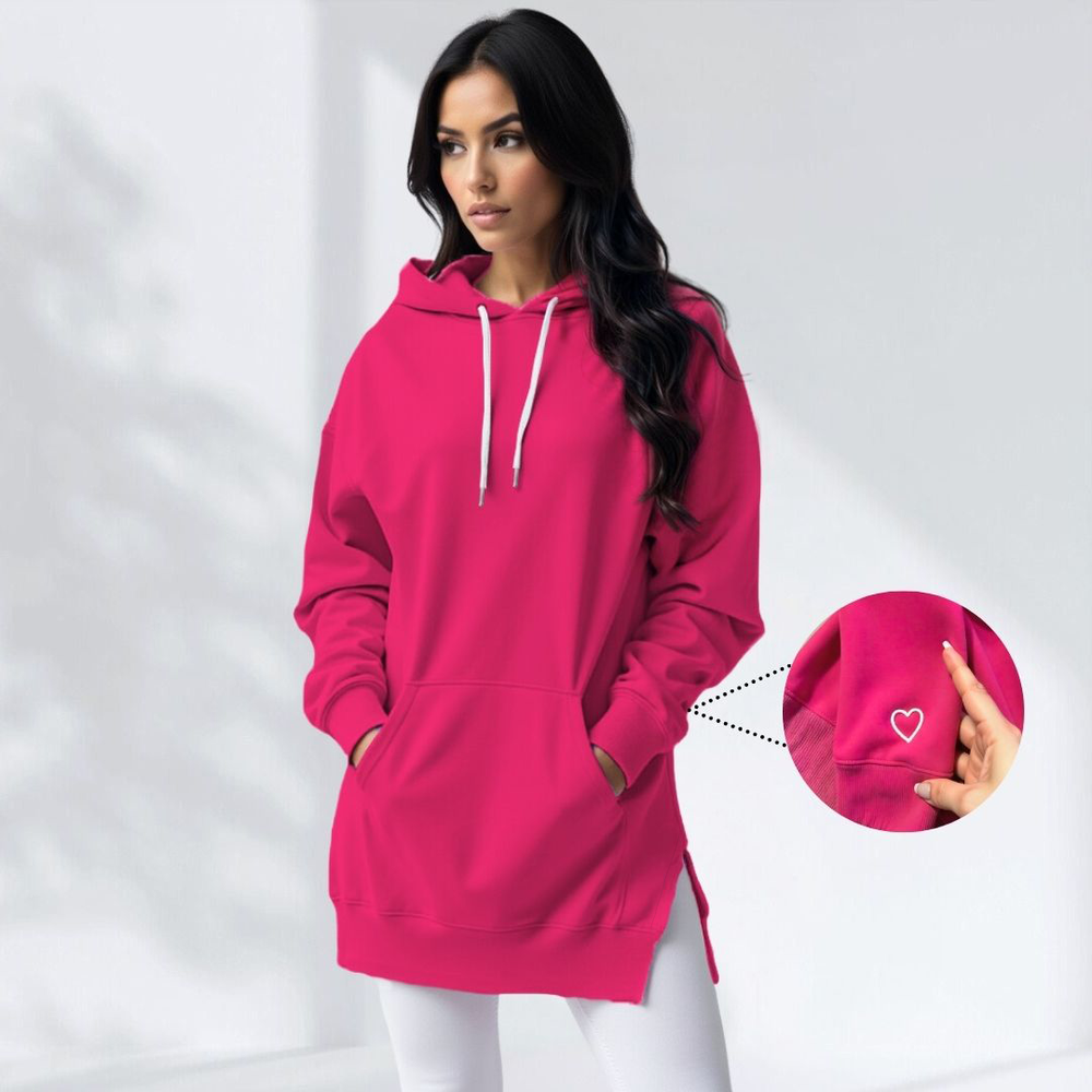 Donna con felpa oversize fucsia, cappuccio e tasche, dettaglio cuore ricamato. Moda casual, abbigliamento autunnale, stile urbano.