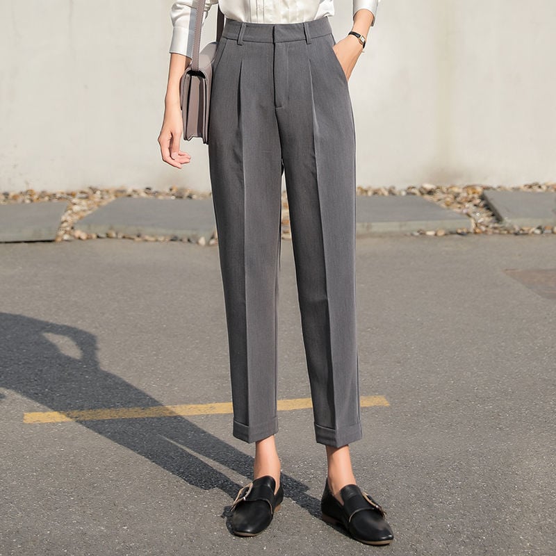 Pantaloni eleganti grigi da donna, taglio dritto, abbinati a mocassini neri e camicia bianca. Moda femminile, abbigliamento formale.