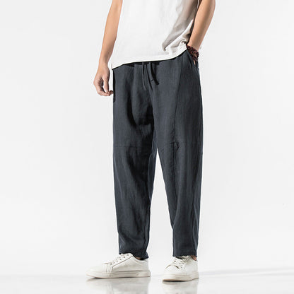 Uomo in pantaloni larghi neri e maglietta bianca, indossa scarpe da ginnastica bianche. Stile casual, moda maschile, abbigliamento comodo.