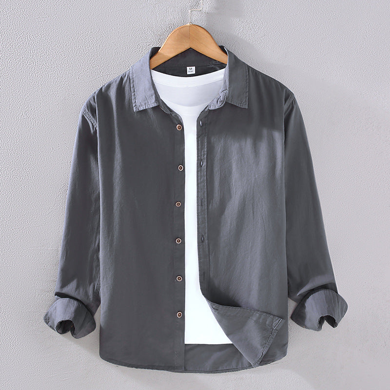 Camicia grigia da uomo in cotone, maniche lunghe, su gruccia, con t-shirt bianca sotto. Elegante, casual, moda maschile, abbigliamento moderno.