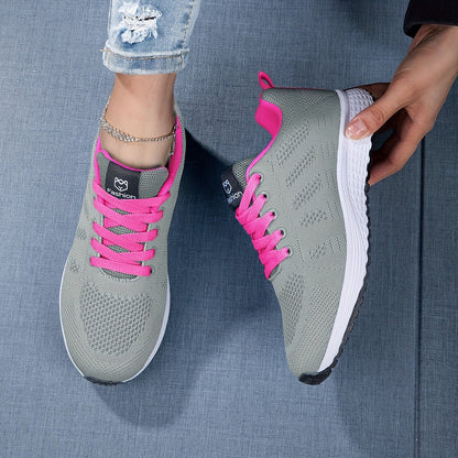 Scarpe da ginnastica grigie con lacci rosa su sfondo blu, indossate da una persona con jeans strappati. Scarpe sportive moda donna, comode e trendy.