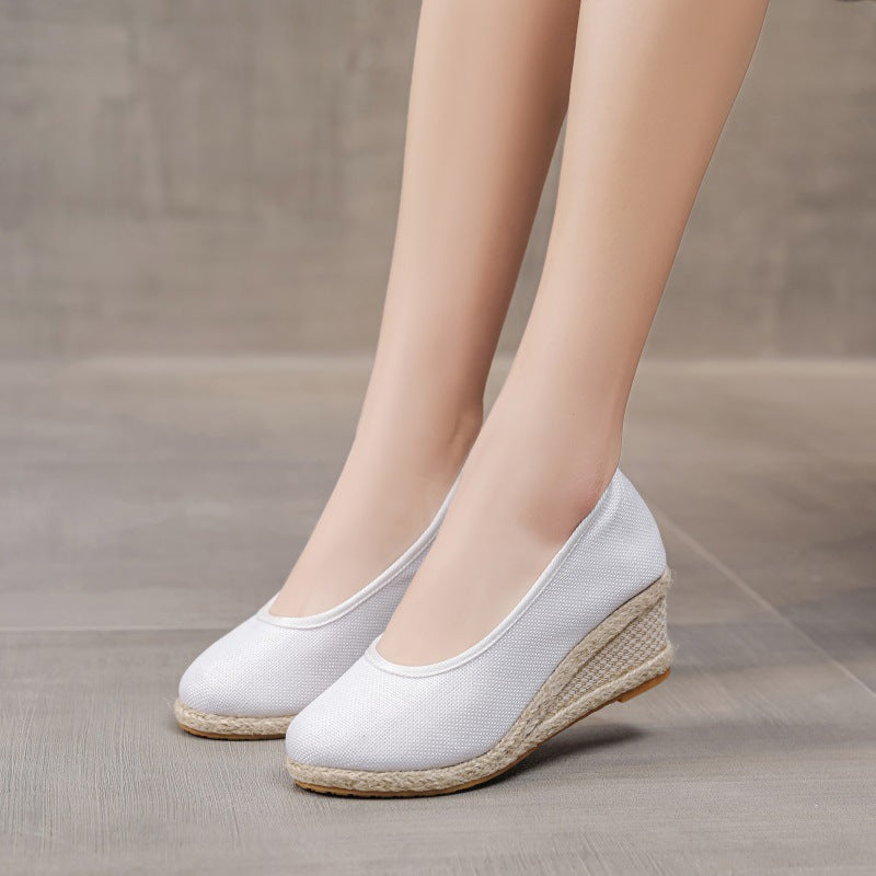 Scarpe con zeppa bianche da donna, eleganti e comode, su pavimento in legno chiaro. Scarpe estive moda, perfette per look casual e formali.