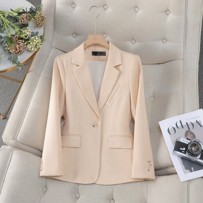 Blazer beige elegante su poltrona, accanto a rivista e fotocamera vintage. Moda donna, abbigliamento formale, stile sofisticato.