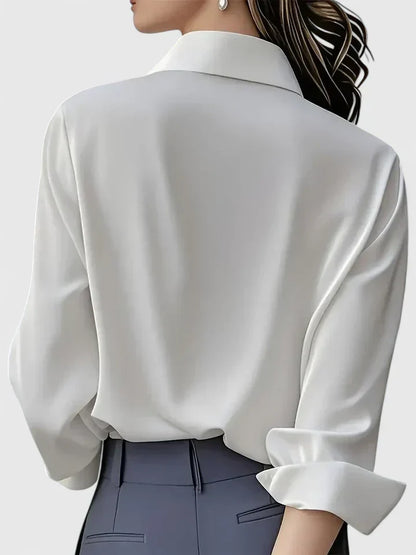 Camicia bianca elegante in seta vista da dietro, indossata da una donna con capelli raccolti. Moda femminile, abbigliamento formale, stile sofisticato.