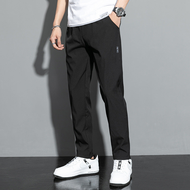 Pantaloni neri eleganti da uomo, abbinati a scarpe da ginnastica bianche e maglietta bianca, moda casual moderna.