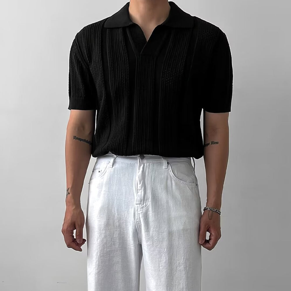 Uomo in camicia nera a maniche corte e pantaloni bianchi, stile casual elegante, sfondo grigio chiaro. Moda maschile contemporanea.