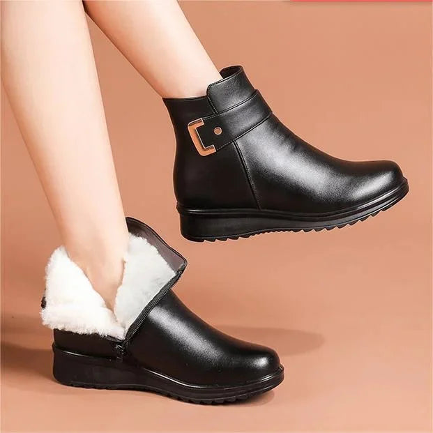 Stivaletti neri in pelle con interno foderato in pelliccia bianca, chiusura laterale con fibbia dorata, suola antiscivolo. Moda invernale donna.
