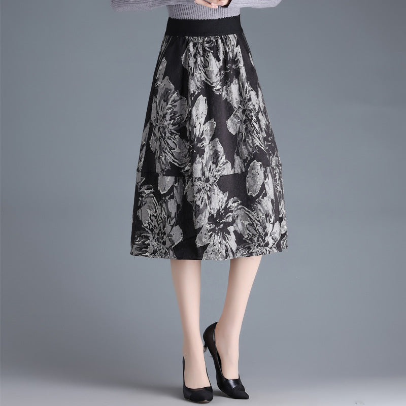 Gonna midi floreale nera e grigia, indossata con maglione grigio e tacchi neri. Moda donna elegante, abbigliamento autunnale chic.