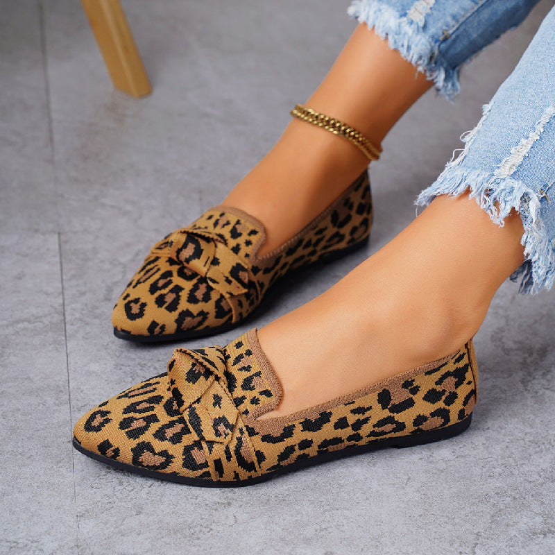 Scarpe mocassini donna leopardate, su pavimento grigio, indossate con jeans strappati. Moda calzature femminili, stile casual elegante.