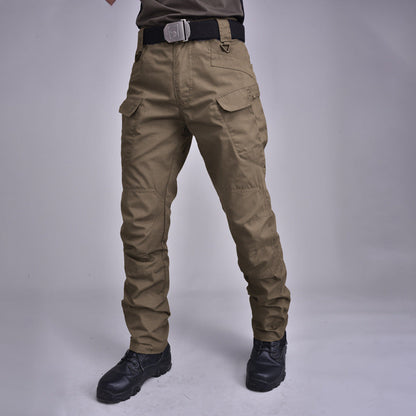 Pantaloni cargo tattici uomo, colore kaki, con tasche multiple e cintura nera, indossati con stivali neri. Abbigliamento outdoor resistente.