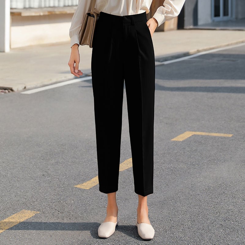 Pantaloni neri eleganti da donna, taglio dritto, abbinati a camicia bianca e scarpe beige, moda urbana, stile casual chic, strada cittadina.