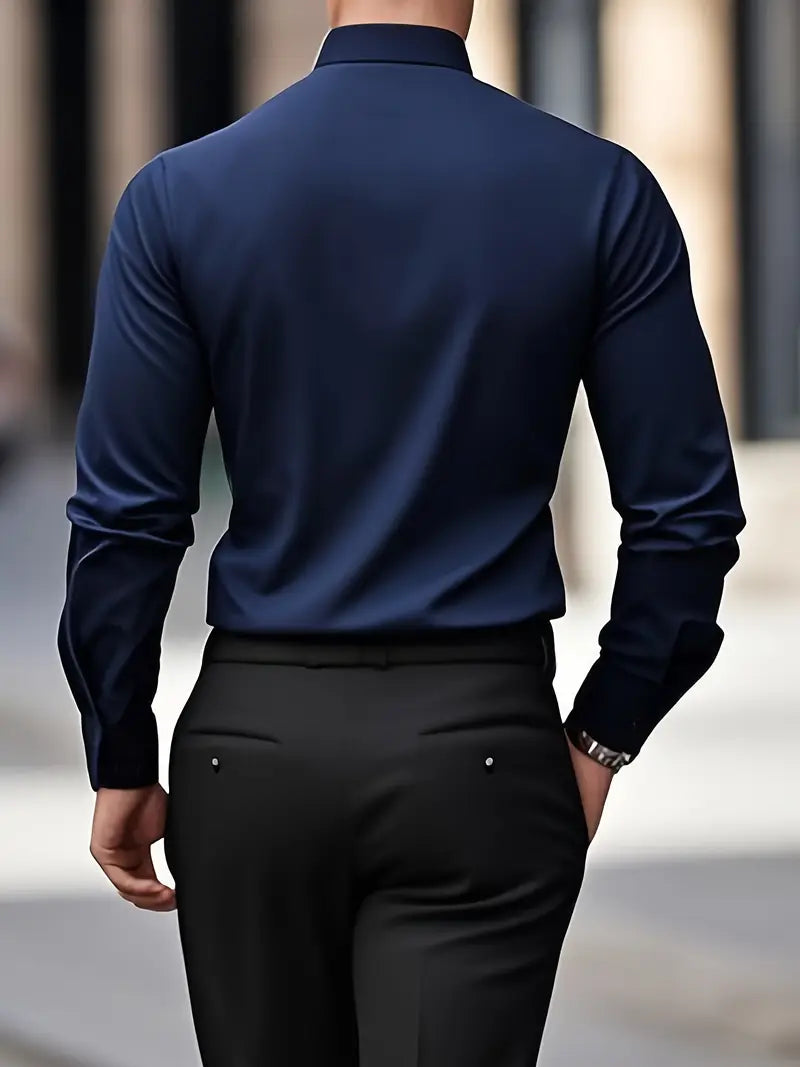 Uomo in camicia blu scuro e pantaloni neri, visto di spalle, cammina in città. Moda maschile elegante, abbigliamento formale, stile urbano.