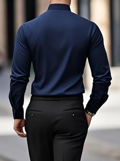 Uomo in camicia blu scuro e pantaloni neri, visto di spalle, cammina in città. Moda maschile elegante, abbigliamento formale, stile urbano.