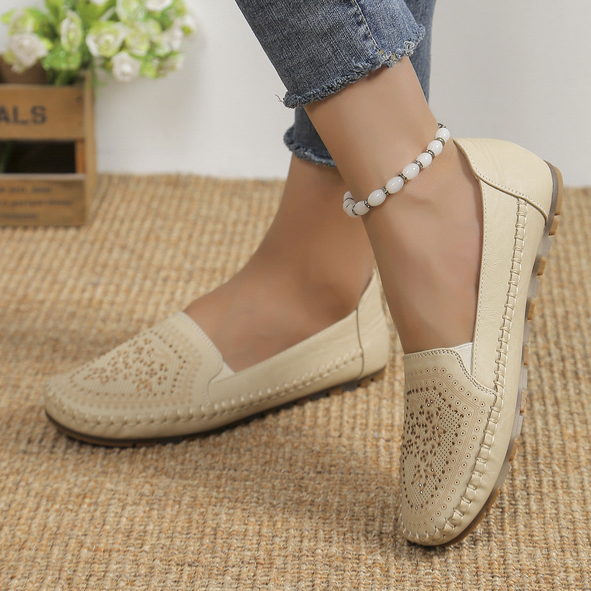 Scarpe mocassini beige da donna in pelle traforata, indossate con jeans. Design elegante e casual, perfette per la moda quotidiana.