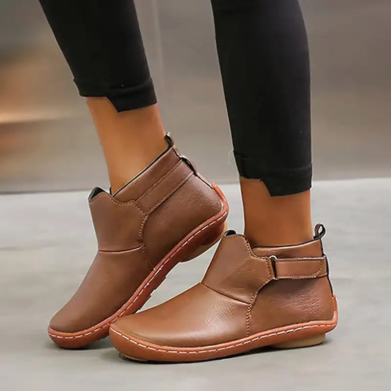 Stivaletti donna in pelle marrone, design casual, suola antiscivolo, indossati con pantaloni neri. Scarpe comode per autunno e inverno.