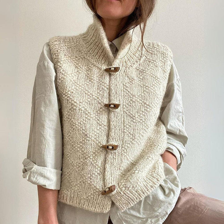 Gilet in maglia di lana bianca con bottoni in legno, indossato su camicia beige. Moda autunnale, abbigliamento casual elegante, stile artigianale.