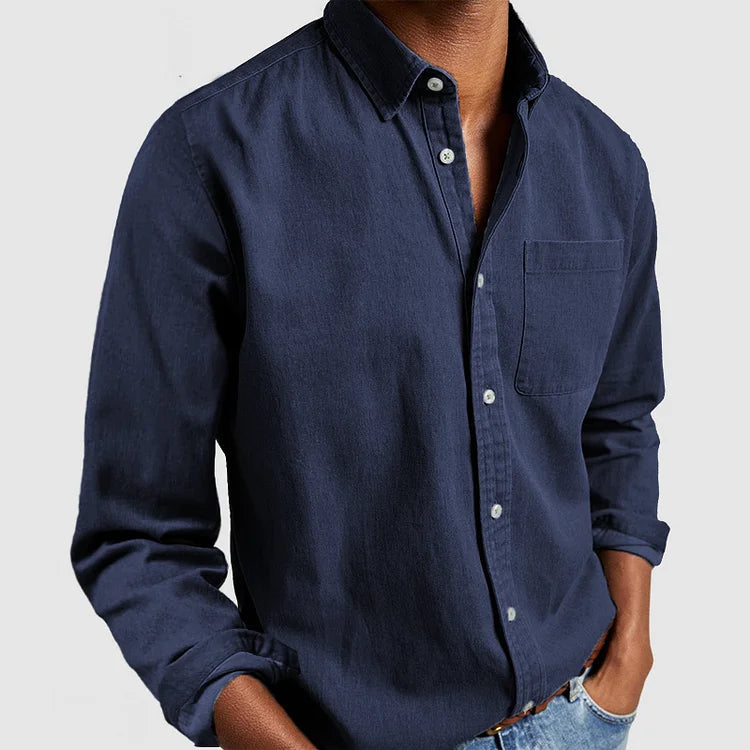 Camicia uomo blu scuro in cotone, maniche lunghe, colletto classico, taschino frontale, abbinata a jeans. Moda casual maschile elegante.