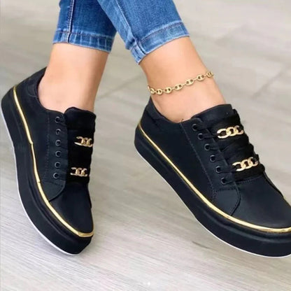Scarpe da ginnastica nere con dettagli dorati, indossate con jeans. Scarpe casual eleganti, moda donna, accessori alla moda.