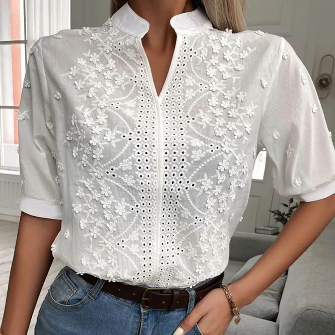 Camicia bianca da donna con ricami floreali, maniche corte, abbinata a jeans. Elegante e casual, ideale per moda estiva e primaverile.