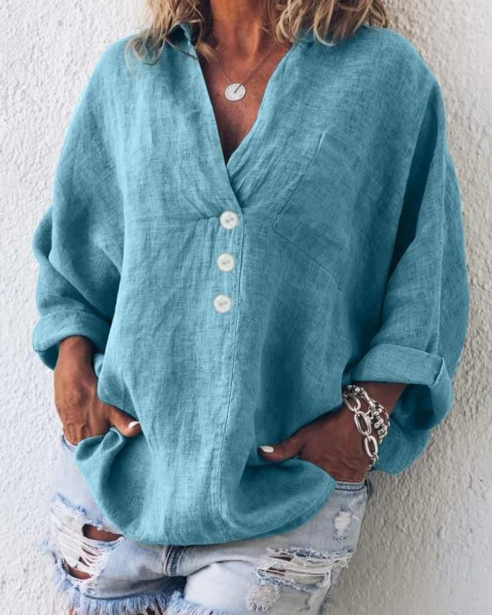 Camicia oversize in lino azzurro con bottoni bianchi, indossata con jeans strappati. Stile casual estivo, moda donna, abbigliamento trendy.