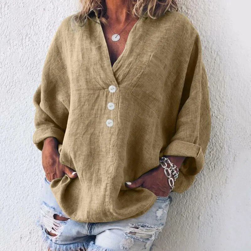 Camicia di lino beige da donna con bottoni bianchi, maniche lunghe arrotolate, abbinata a jeans strappati. Stile casual e moderno.