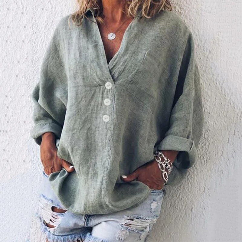 Donna con camicia di lino verde oversize, bottoni bianchi, maniche arrotolate, abbinata a shorts di jeans strappati. Stile casual estivo.