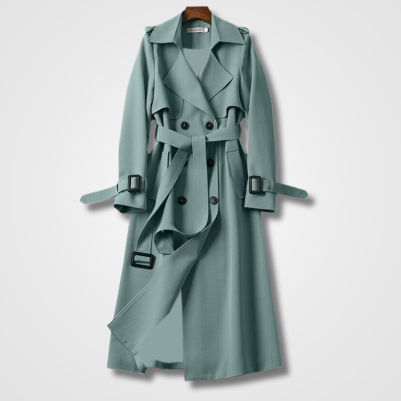 Cappotto trench lungo verde acqua, doppio petto, con cintura e bottoni neri, appeso su gruccia. Elegante e moderno, ideale per moda autunnale.