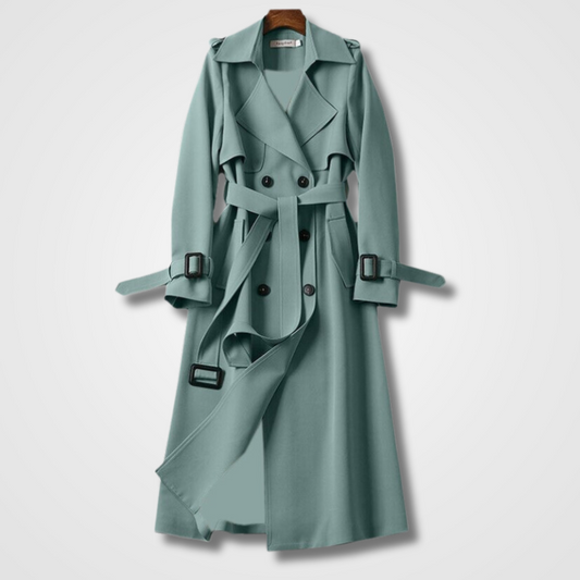 Cappotto trench lungo verde acqua, doppio petto, con cintura e bottoni neri, appeso su gruccia. Elegante e moderno, ideale per moda autunnale.