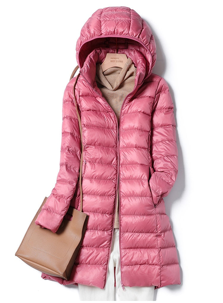 Giacca invernale rosa con cappuccio, imbottita e trapuntata, abbinata a maglione beige e borsa marrone. Moda donna, abbigliamento caldo.