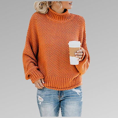 Donna con maglione arancione a maglia grossa, jeans strappati e caffè da asporto. Moda autunnale casual, stile urbano, comfort quotidiano.