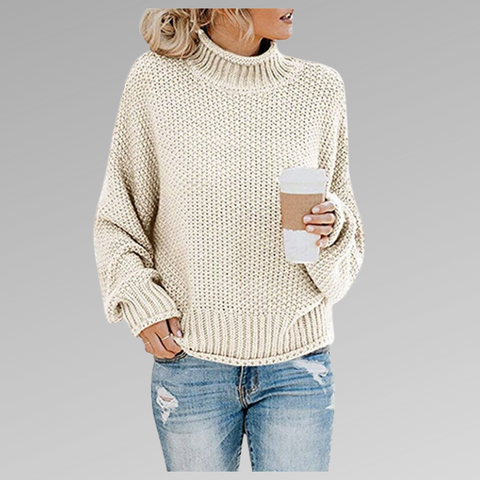 Donna con maglione a maglia beige, jeans strappati e caffè da asporto. Moda casual autunnale, stile urbano. Sfondo grigio chiaro.