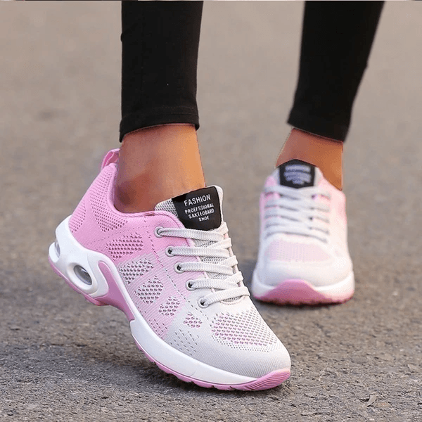 Scarpe da ginnastica rosa e bianche da donna su strada asfaltata, design traspirante, suola ammortizzata, moda casual sportiva.