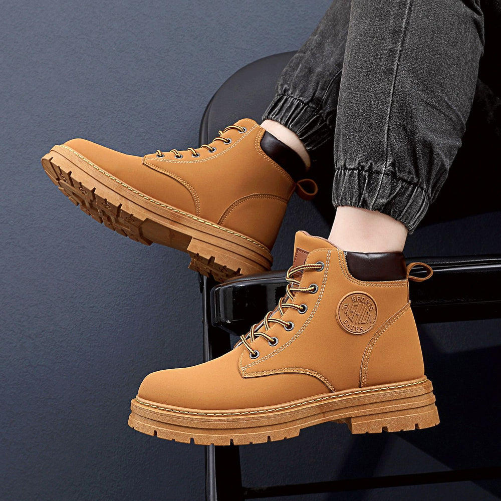 Scarponcini in pelle marrone chiaro con suola robusta, indossati con jeans neri. Scarpe da uomo eleganti e resistenti, ideali per l'inverno.