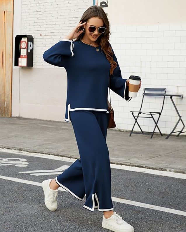 Donna con occhiali da sole indossa un completo blu con bordi bianchi, cammina su marciapiede con caffè in mano. Moda casual urbana, street style.