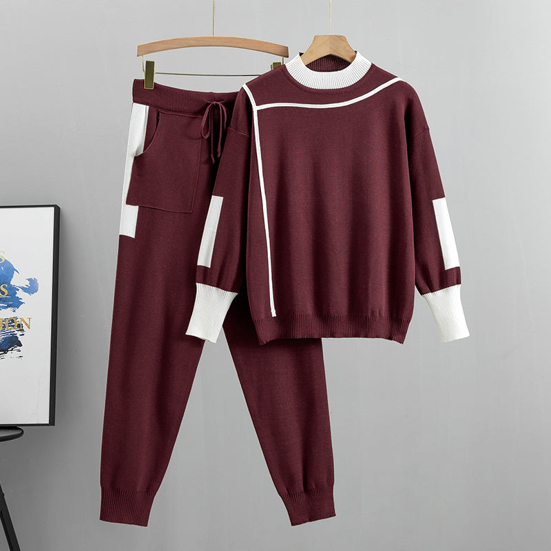 Completo sportivo donna bordeaux con dettagli bianchi, composto da maglione a maniche lunghe e pantaloni con tasca, appeso su grucce di legno.