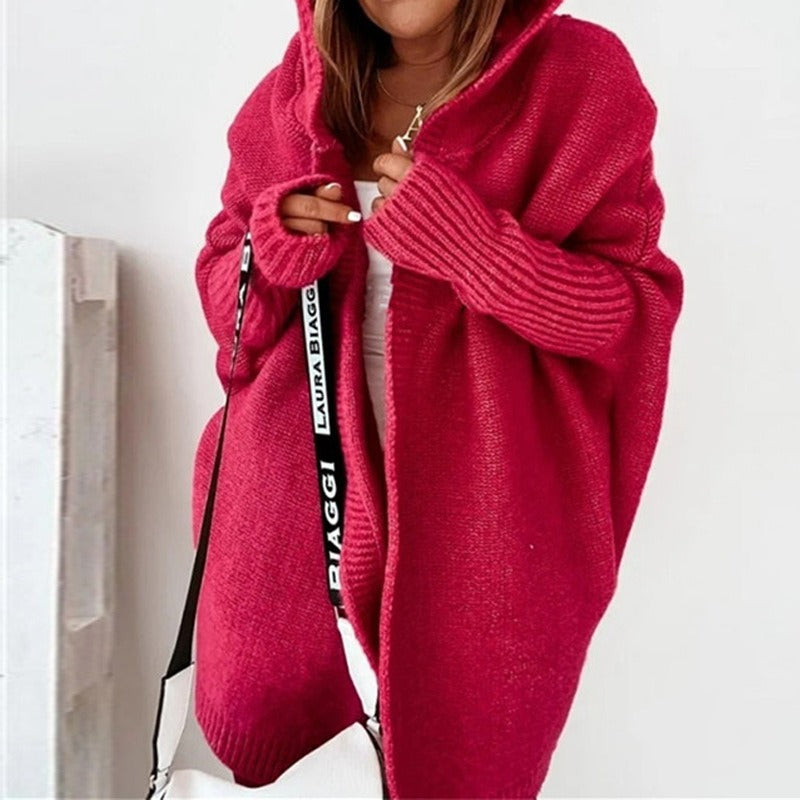 Donna con cardigan oversize rosso, cappuccio e borsa bianca. Moda autunnale, abbigliamento casual, stile confortevole.