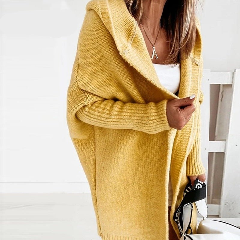 Donna con cardigan giallo oversize, maglia bianca, collana con ciondolo "A", borsa a mano. Moda autunnale, abbigliamento casual elegante.