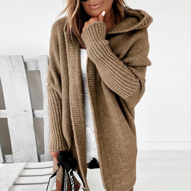 Donna con cardigan marrone a maglia grossa, cappuccio e maniche lunghe, su sfondo bianco. Moda autunnale, abbigliamento casual elegante.