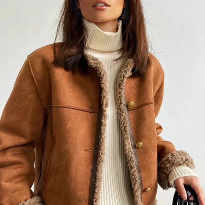 Giacca invernale marrone con bottoni dorati e interno in pelliccia sintetica, indossata su maglione a collo alto bianco. Moda autunnale donna.