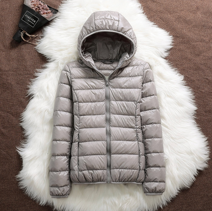 Giacca invernale imbottita grigia con cappuccio su sfondo di pelliccia bianca, moda donna, abbigliamento caldo, stile casual, tendenza autunno inverno.