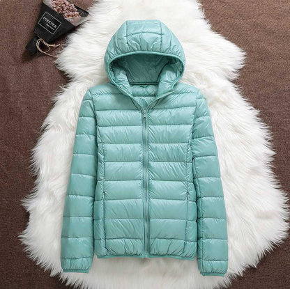 Giacca invernale imbottita verde menta su sfondo di pelliccia bianca, con cappuccio e zip frontale. Moda donna, abbigliamento caldo e trendy.
