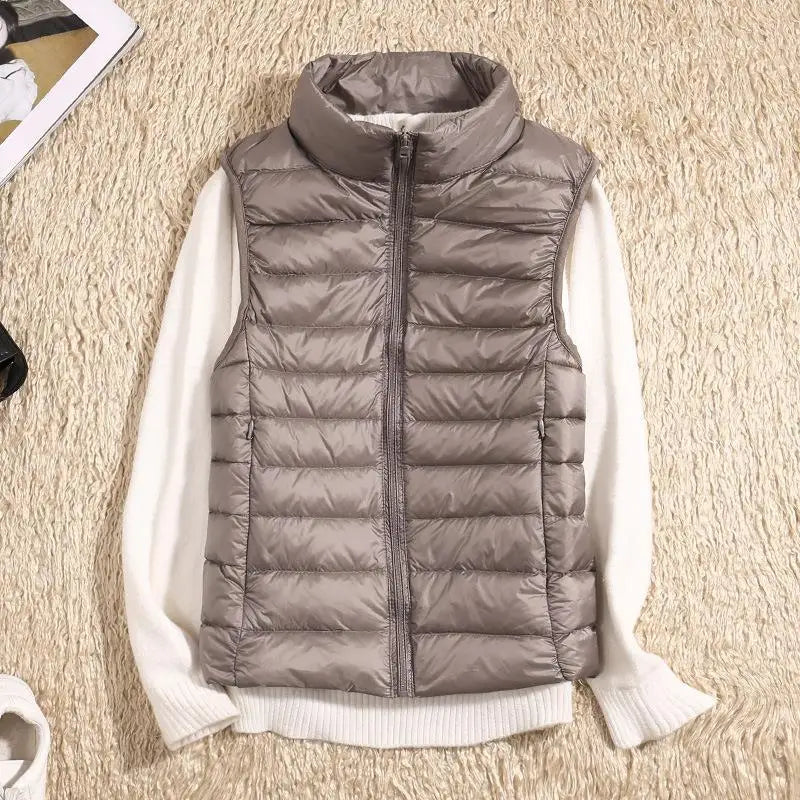 Gilet imbottito grigio su maglione bianco, moda autunnale, abbigliamento casual, tessuto trapuntato, stile moderno, outfit caldo e confortevole.