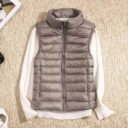 Gilet imbottito grigio su maglione bianco, moda autunnale, abbigliamento casual, tessuto trapuntato, stile moderno, outfit caldo e confortevole.