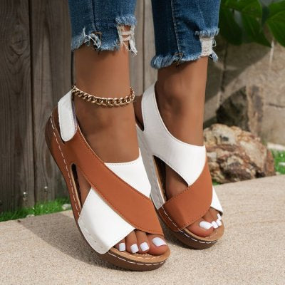 Sandali estivi donna in pelle bicolore marrone e bianco, con zeppa e cinturino alla caviglia, indossati con jeans strappati.