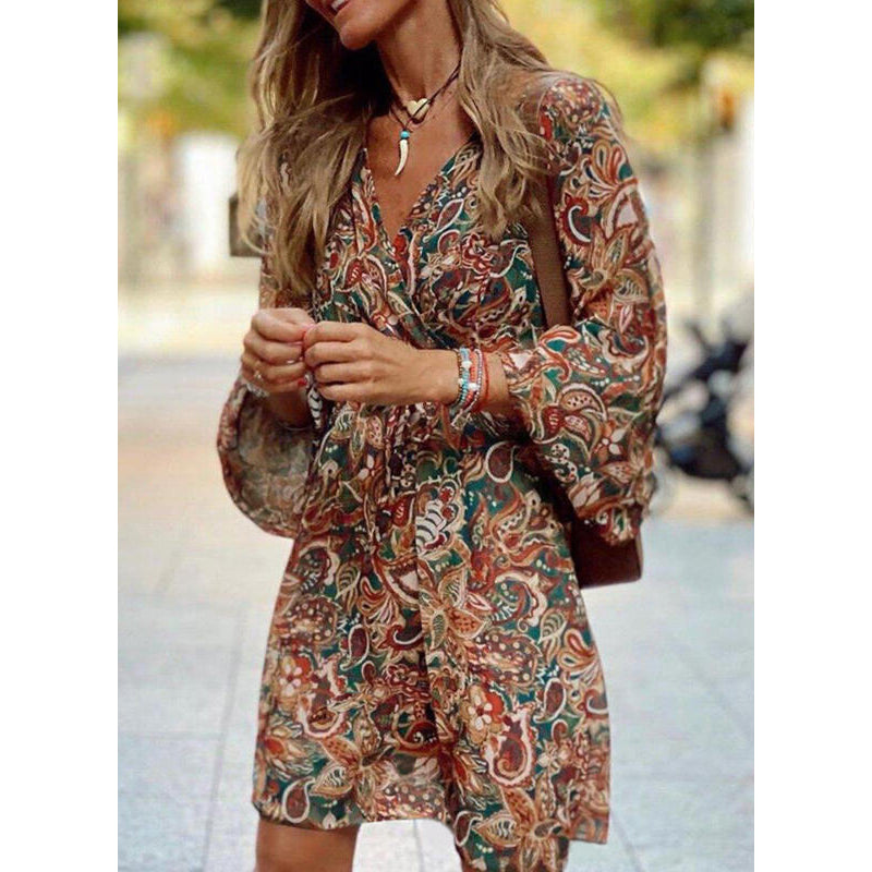 Donna con abito boho a fantasia floreale, maniche lunghe, in strada. Stile casual chic, moda autunnale, accessori eleganti.