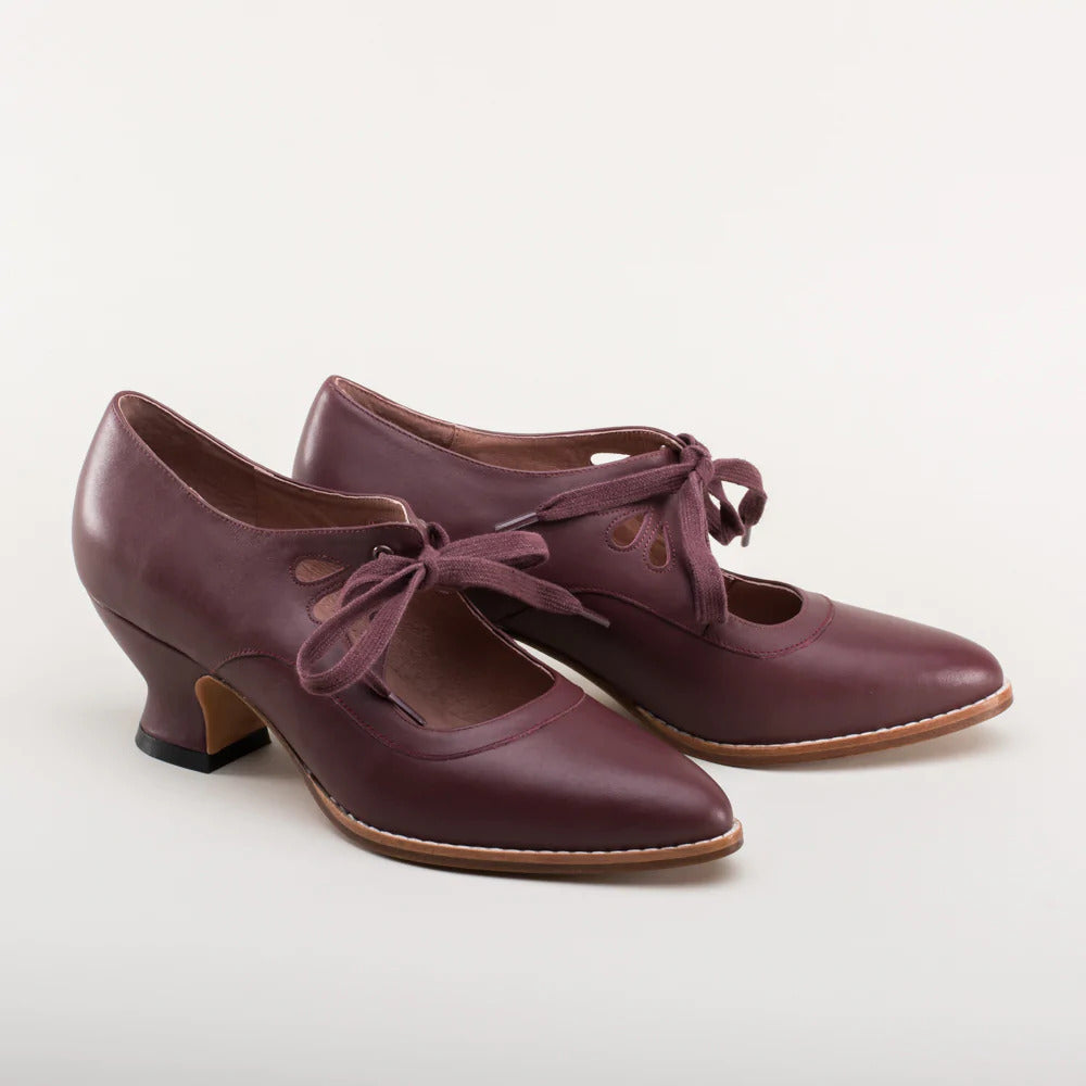 Scarpe da donna in pelle bordeaux con tacco medio, lacci decorativi e design vintage. Calzature eleganti per look retrò e moda autunnale.