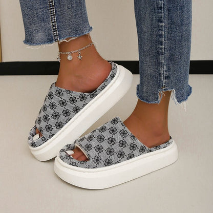 Jeans strappati e sandali con zeppa bianchi e grigi a motivo floreale, cavigliera con ciondoli. Moda estiva casual, calzature trendy.