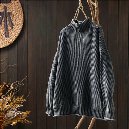 Maglione grigio a collo alto in maglia spessa appeso su sfondo di legno scuro, moda autunno inverno, abbigliamento caldo e accogliente.