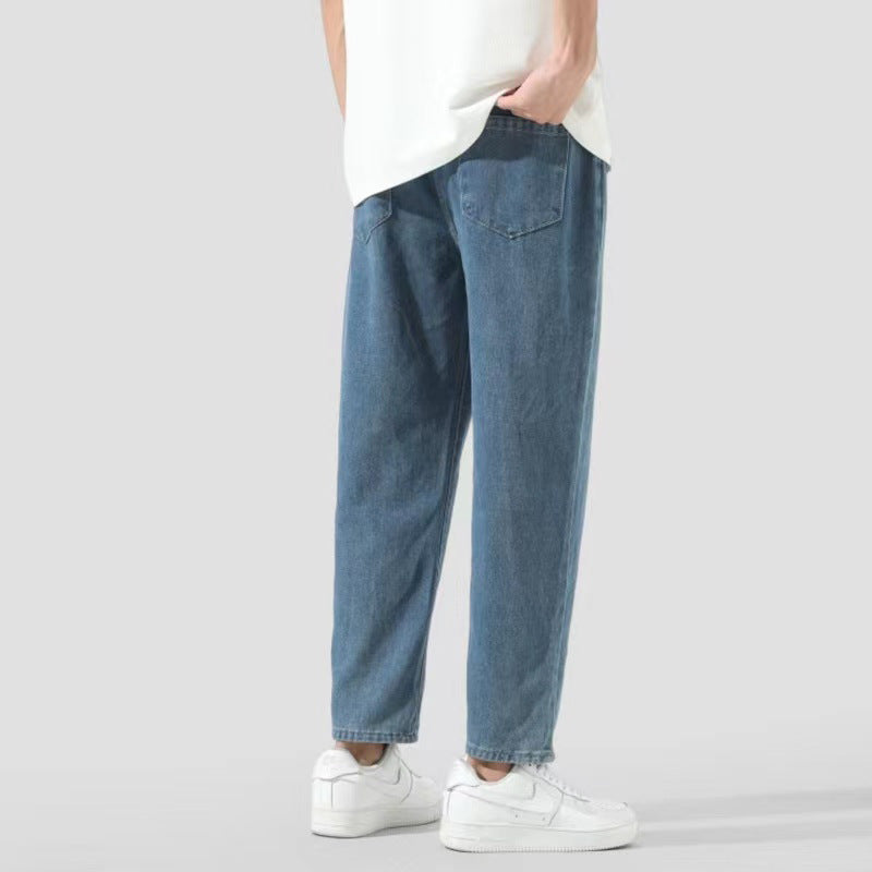 Jeans larghi blu da uomo, stile casual, abbinati a scarpe bianche e maglietta bianca. Moda maschile, abbigliamento quotidiano.